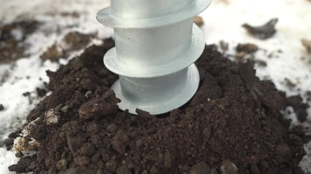 Screwing screw piles into the ground at a construction site in winter. Soil drilling. Telescope crane. Drilling under bored piles and under fence posts, installation of screw piles 