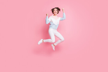 Fototapeta na wymiar Full length photo of funky lucky young woman wear sweater jumping rising fists isolated pink color background