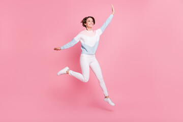 Fototapeta premium Full length photo portrait of excited girl jumping up isolated on pastel pink colored background