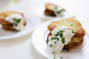 Potato pancakes with sour cream and herbs on plate
