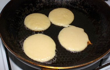 Pancakes are fried in oil in a frying pan.