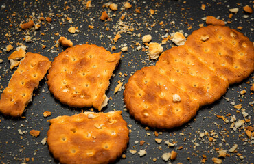 Two delicious crackers are on top of cookie crumbs. Cracker on a black background. Donated crackers