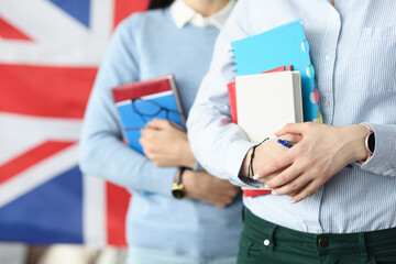 Two students hold notebooks against background of flag of England