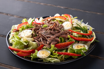 Beef tongue salad with fresh vegetables on a plate.