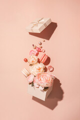 Floral explosion, flowers in motion from a gift box against a peach background. Muted monochrome, Minimal spring concept, flat lay.
