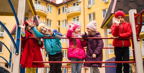 Obraz na płótnie Canvas the smiling kids are standing together on the playground equipment