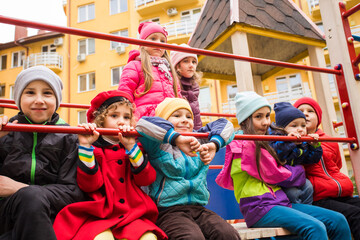 Fototapeta premium the smiling kids are standing together on the playground equipment