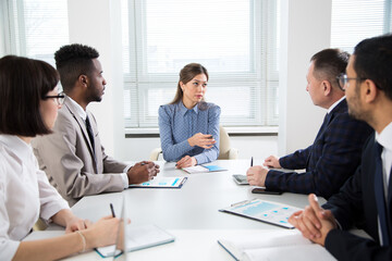 Group of business people sitting around the office desk and discussing the project