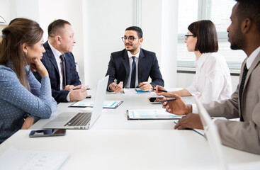 Group of business people sitting around the office desk and discussing the project