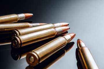 Rifle bullets or cartridges on black shiny background - obrazy, fototapety, plakaty