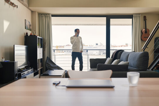 middle-aged man talking on the phone while working from home