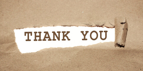 The text Thank You appearing behind torn brown paper
