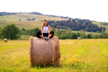Naklejka na ściany i meble Young woman at the country side on a haystack 