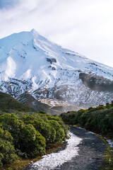 Gravel trail heading towards magnificent snow covered cone of Mt Taranaki. Egmont National Park, New Zealand