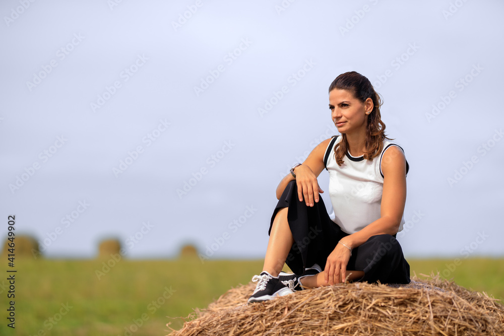 Wall mural young woman at the country side on a haystack