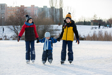 Happy children, skating on a frozen lake in the park