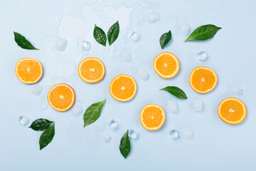 Natural healthy juicy organic orange slices and ice on blue background.