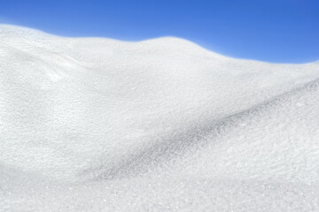 Snow texture or winter white background with wave and blue sky