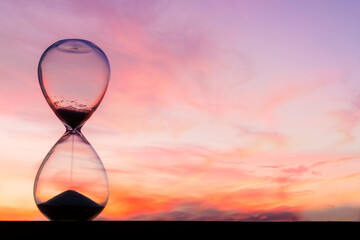 Time passing at sunset with hourglass - obrazy, fototapety, plakaty