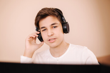 Close up of steamer in wireless headphones speak with frieds while playing game. Teenage boy stay at home and play all day