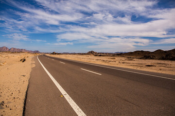 Fototapeta premium Road in the sahara desert of Egypt. Conceptual for freedom, enjoying the journey. Empty road. Freeway, Highway through the desert