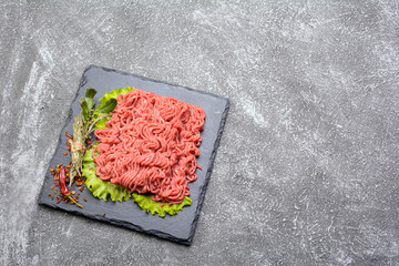 Fresh minced pork and beef, garnished with garlic, red pepper and dill on a slate stone.Dark...