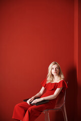 Young adult woman sitting on a chair and holding laptop