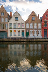 Fototapeta na wymiar Twin facades but painted in different tones. Typical residential homes next to a channel in Brugge, Belgium.