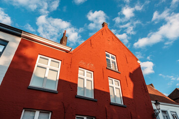 Fototapeta na wymiar Close-up of a red vibrant color facade made of bricks against the blue sky in Bruges, Belgium.