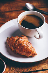 Cup of Black Coffee and Fresh Croissant on Rustic Table