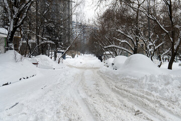 Moscow street with cars standing on a roadside covered with snow after a hard blizzard in winter