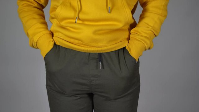 Close up of unrecognizable woman put her hands in her pockets of pants. Front view on body part of young female showing her empty pockets on gray background.