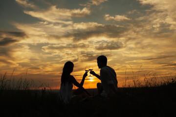 Fototapeta na wymiar Attractive couple enjoying romantic sunset at the summer picnic in the countryside.