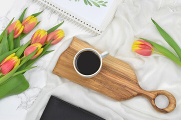Flowers, coffee, notebook on light textured background, flat lay.