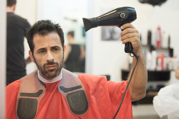 Uomo da un parrucchiere si asciuga i capelli da solo con il phon