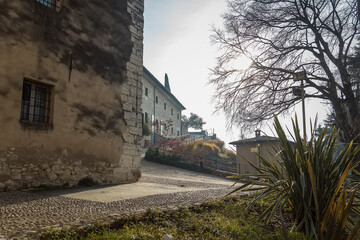 Part of the castle of the city of Brescia on a sunny winter day. A view from the park. Castello di Brescia, Lombardy, Italy. Medieval castle with battlements, a tower, drawbridge and ramparts. 