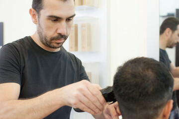 Obraz na płótnie Canvas Uomo dal parrucchiere mentre gli vengono tagliati i capelli con un rasoio elettrico 