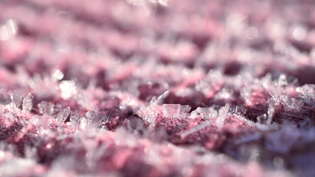 Delicate ice cristals on pink purple fabric in sunshine as background	
