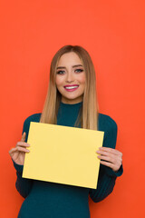 Naklejka premium Beautiful Smiling Young Woman Is Holding Yellow Sheet Of Paper.