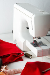 Modern sewing machine with red and gray fabric, measuring tape and thread, cutting and sewing at home, home leisure and hobby