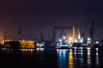 Fototapeta na wymiar NIGHT IN SHIPYARD - Repair dock, ships and cranes on the quays 