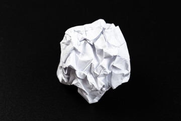 A crumpled paper ball in a black background