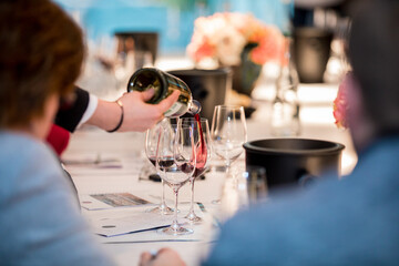 close up on a wine glasses, bottle and red wine being poured