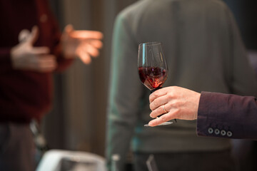Close up on a hand holding a glass of red wine