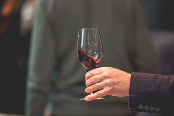 Close up on a hand holding a glass of red wine