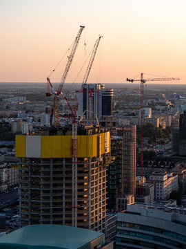 Skyscraper construction process in Warsaw. The inner structure and the cranes are visible. Warm colors, sunset image.