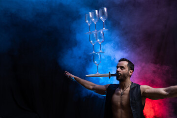 Man hold knife in the mouth and keep in balance wineglasses on it. concentration © Hladchenko Viktor