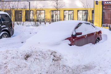 Moscow. Russia. Snowfall in February. Car in a snowdrift. After a heavy snowfall, the car was covered with snow from all sides. To leave you will have to work with a shovel