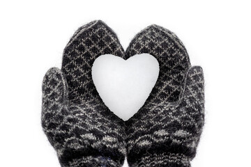 Hände in Handschuhen mit Norweger Muster halten ein Herz aus Schnee, Schneeherz mit Blendenflecken. geringer Schärfentiefe