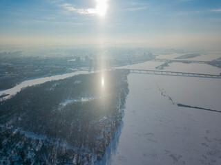 Light pillar from the sun over the Dnieper river in Kiev. Aerial drone view. Winter sunny morning.